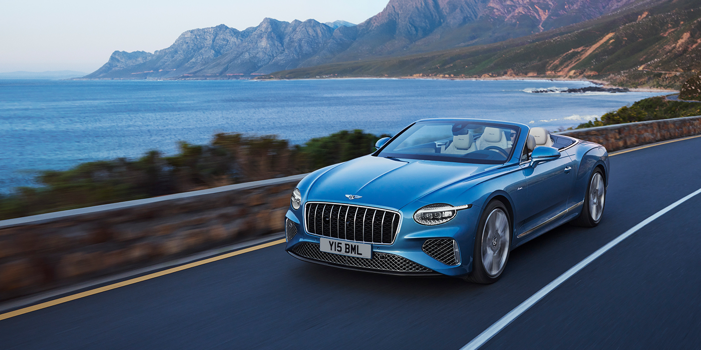 Bentley Lyon New Bentley Continental GTC Azure convertible in Light Windsor blue paint with 22 inch Azure wheels and chrome grill, driving dynamically by the sea