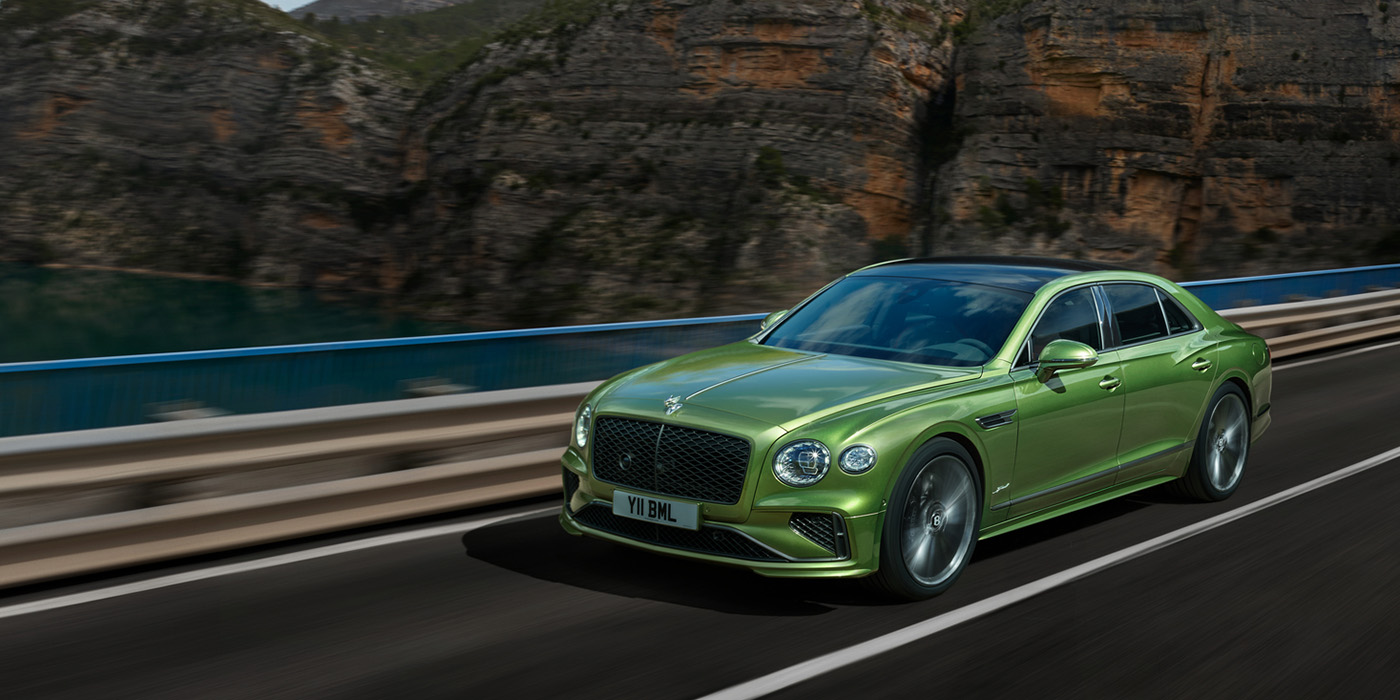 Bentley Lyon Bentley New Flying Spur Speed v8 hybrid sedan driving dynamically on a mountain road in Tourmaline Green paint