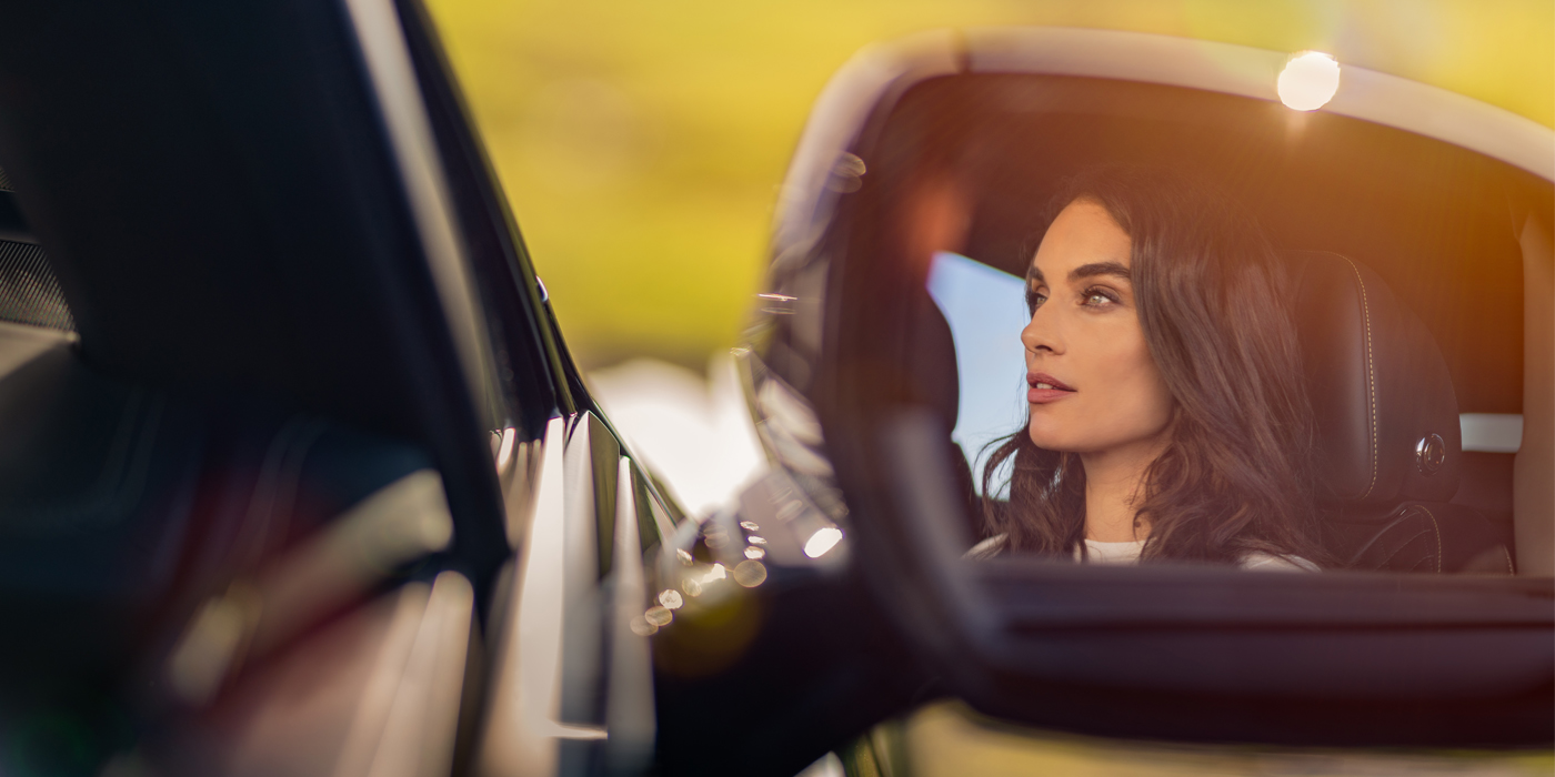 Bentley Lyon profile of dark haired woman's face in mirror of Bentley car in sunlight