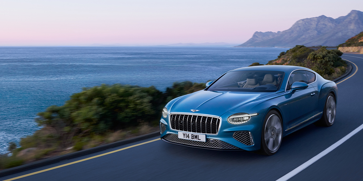 Bentley Lyon New Bentley Continental GT Azure coupe in Light Windsor blue paint with 22 inch Azure wheels and chrome grill, driving dynamically by the sea