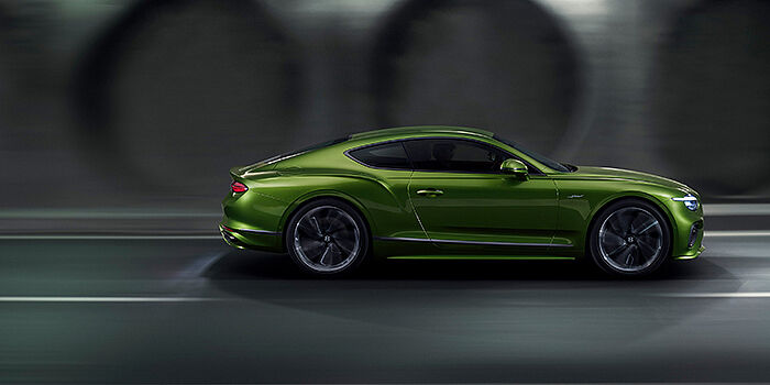  Bentley Lyon Bentley Continental GT coupe in Tourmaline Green paint driving in profile on a dark road