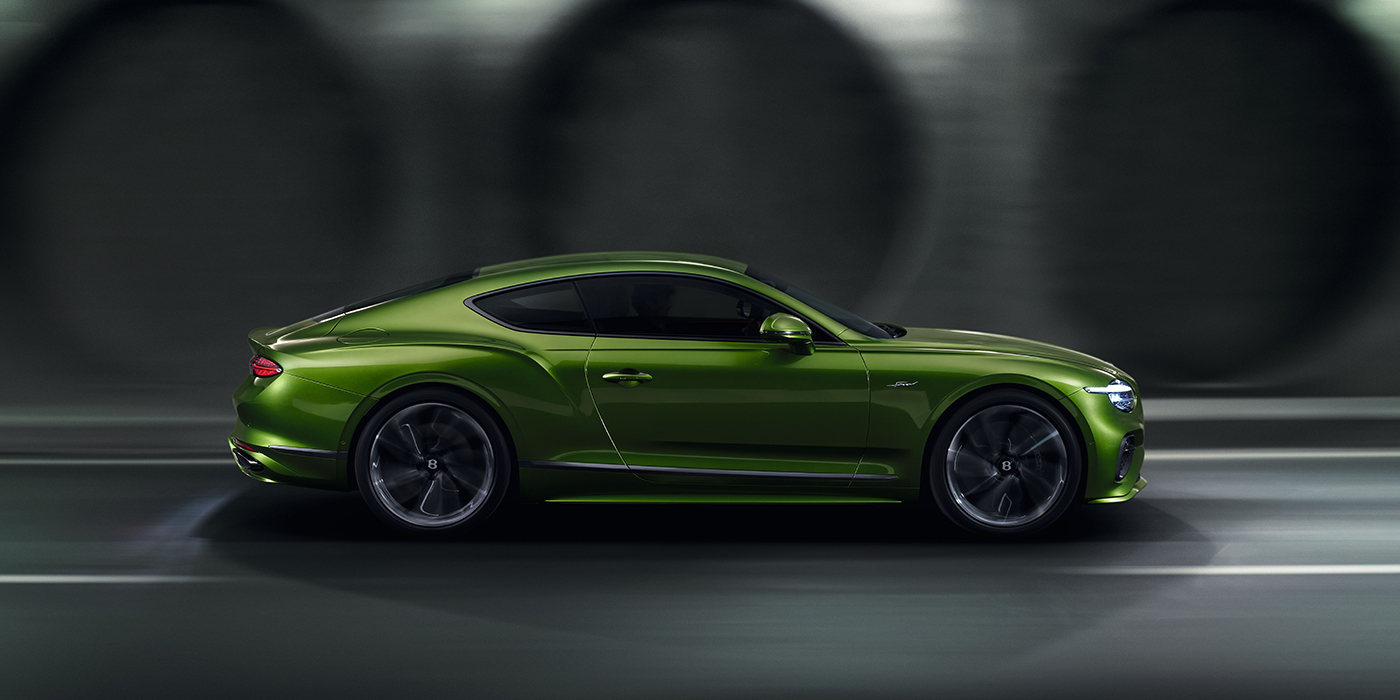 Bentley Lyon Bentley Continental GT coupe in Tourmaline Green paint driving in profile on a dark road